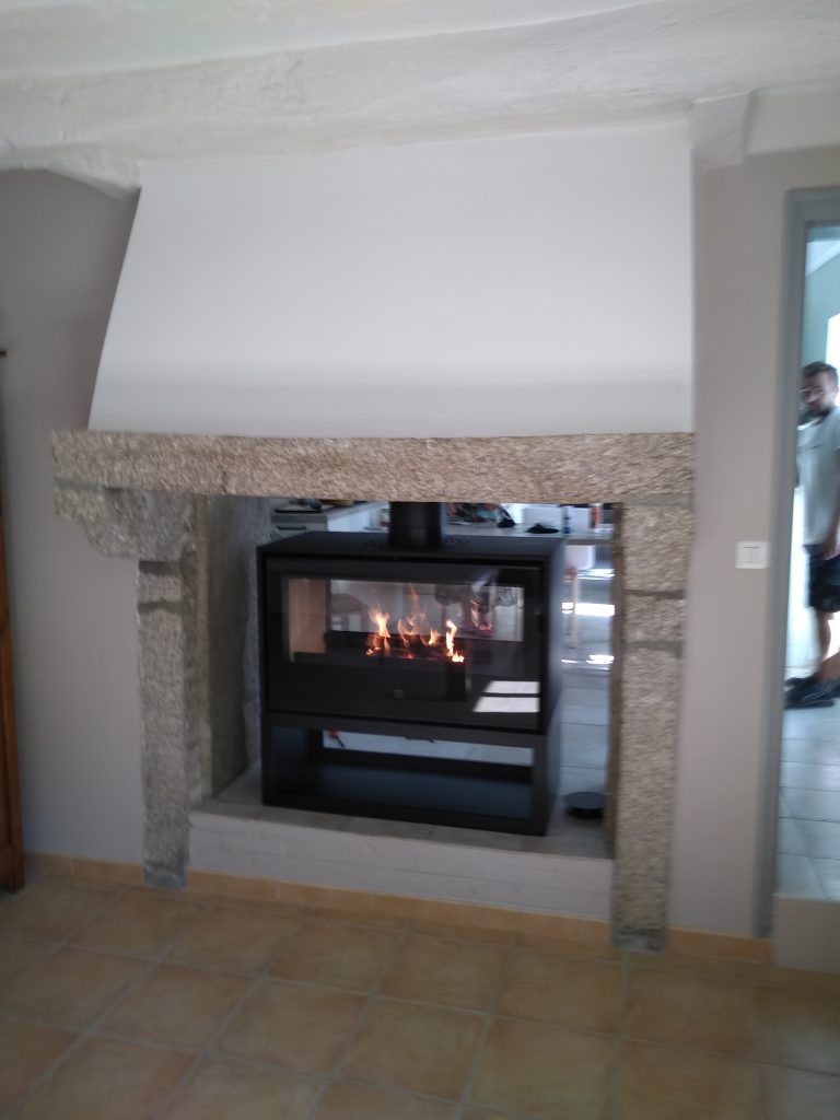 Installation d'un poêle à bois 1000 double face Axis dans une cheminée en granit par l'entreprise Desobeaux à Largeasse